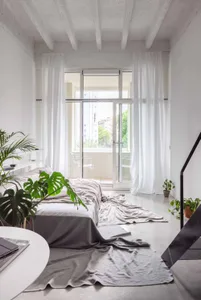 A minimalist bedroom with concrete floor and white walls.