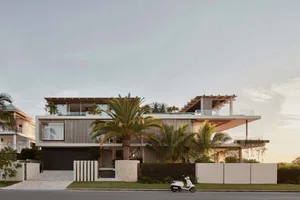 A modern house with a glass and metal exterior featuring a spacious balcony.