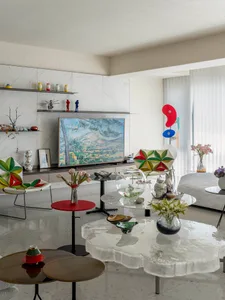 A modern living room featuring glass tables and abstract art.