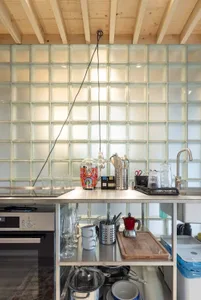 A minimalist modern kitchen with metal cabinets and a glass backsplash.