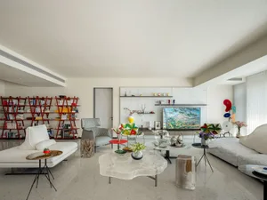 A modern living room with a marble interior featuring contemporary furniture, a plush white sofa, a colorful armchair, and de