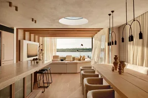 Modern living room with a large sectional sofa, a coffee table, and a mounted television on a wooden wall, with sheer curtain