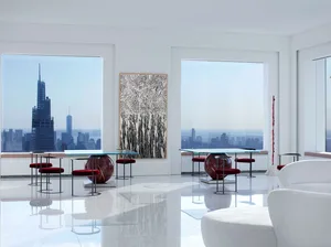 A modern living room with art deco design elements, featuring glass tables, metal chairs, and fabric seating.