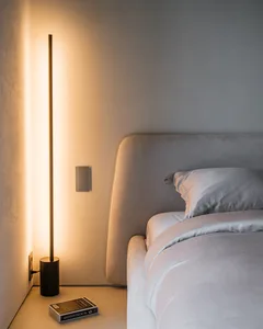 A modern bedroom with a grey upholstered headboard made of velvet fabric and a floor lamp providing a warm glow.