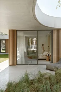 Modern bedroom with wooden floors, concrete walls, and glass sliding doors.