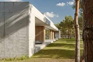 A modern residential exterior featuring clean lines, concrete walls, and large glass windows.