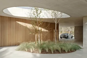 Circular wooden roof interior with plants and a Porsche 911 in the background.