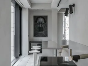Modern kitchen area with white marble bar, seating, and a black painted portrait on the wall.