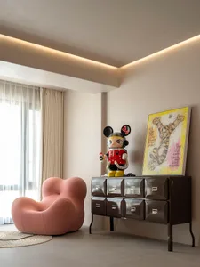 A modern living room featuring a pink cushion and decorative elements such as a cabinet with drawers, a framed picture, and a