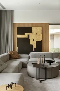 Modern living room with a grey sectional sofa, wooden coffee table, and abstract art on the wall.