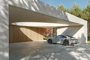 White Porsche parked in a minimalist, modern, concrete carport with wood accents.