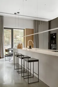 Minimalist kitchen with white marble countertops and sleek black stools.