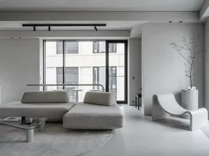 A minimalist living room with concrete flooring and white furniture.