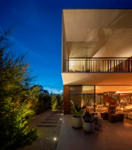 Modern residential exterior with concrete structure and illumination at dusk.