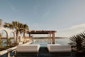 A serene residential area featuring an infinity pool with glass surroundings and a stone patio.