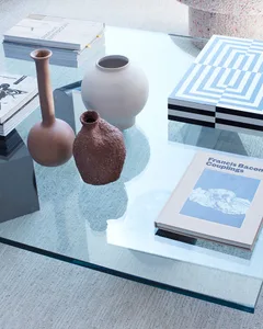A modern coffee table featuring glass and ceramic vases and books.