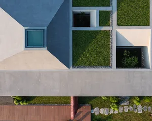Aerial view of a modern house exterior with concrete and grass.