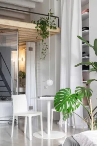 A minimalistic apartment living space with concrete flooring and white furniture.
