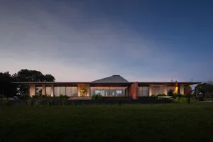 A modern house with a glass exterior under a dusk sky.
