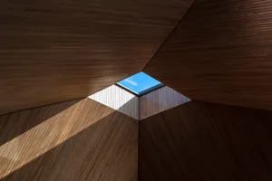 Modern interior design featuring a wooden ceiling with a skylight, providing a view of the city skyline.