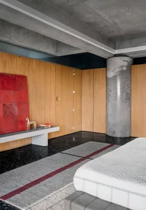 Close-up of a modern bedroom with a concrete ceiling, concrete floor, and wooden walls.