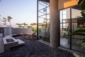 Concrete patio with gravel, modern glass walls, and potted plants