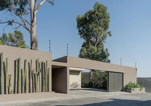 A minimalist concrete garage with a modern design and green cactus plants on the wall.
