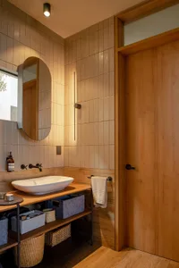 Modern bathroom with minimalist design, featuring neutral-colored tiles and wooden accents.