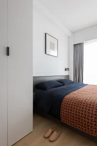 A minimalist bedroom featuring fabric bedding, wooden flooring, and metal elements