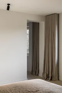 A minimalist bedroom with textured linen curtains, showcasing a serene and stylish bedroom design.