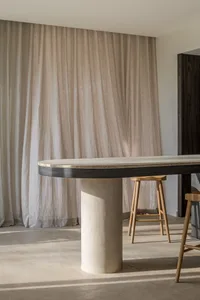 A minimalist lounge area with a textured concrete table and wooden stools.