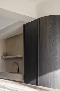 A minimalist interior with dark wooden cabinetry and a concrete countertop.
