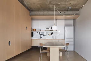 Modern minimalist kitchen with concrete countertops, wooden cabinets, and metal fixtures.