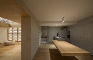 A modern minimalist kitchen with solid wooden countertops and cabinets, illuminated by soft under-cabinet lighting, and featu