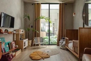 A minimalist living room with a play area for a young child, featuring a wooden crib, a colorful rug, and various toys.