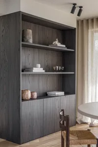 A modern bookshelf made of dark wood with decorative items on the shelves.