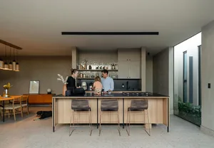 A modern family kitchen featuring concrete and glass materials with a focus on natural lighting and organic shapes.