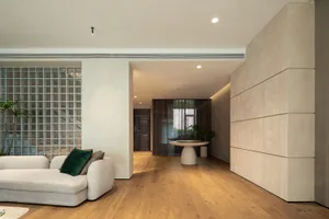 Modern living room featuring a white couch, wooden floor, and a glass block wall with a green plant