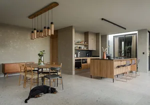 Minimalist residential kitchen featuring wooden surfaces with black countertops and a central island.