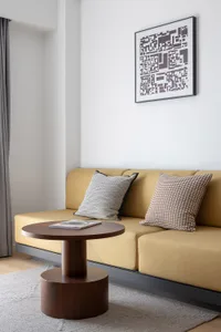 Modern living room with a yellow sofa, gray curtains, and white walls.