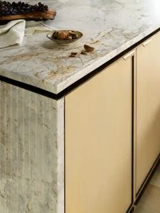 A modern kitchen featuring a marble countertop with a bowl of walnuts and grapes.