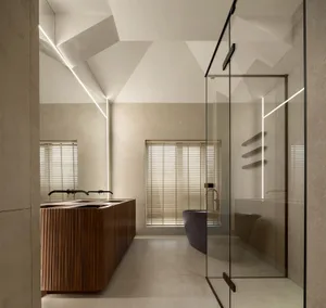 Photograph of a minimalist bathroom with concrete walls and a glass shower enclosure.