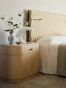 Bedroom with minimalist design featuring a wooden nightstand with a marble top, a bed with a striped fabric headboard, and fl