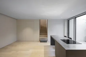 Modern minimalist kitchen with wooden flooring and minimalist design elements.