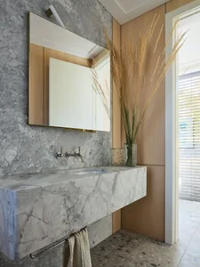 Modern bathroom interior with marble sink, mirror, and vase with dried plants.