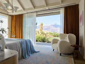 Modern bedroom featuring textured fabric bedding, wood details, and glass window