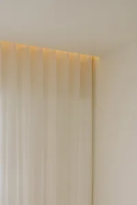 White sheer curtain panels hanging from a ceiling rail.