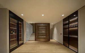 Modern wine cellar featuring wooden floors and walls, with a glass block wall and illuminated shelves.