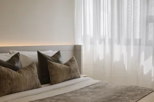 A minimalist bedroom featuring plush fabric bedding, elegant pillows, and a soft headboard.