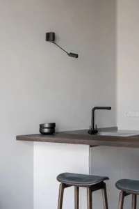 Modern kitchen with a wooden countertop, black faucet, and wall-mounted lamp.